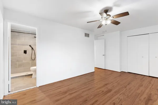 an empty room with wooden floor fan and windows