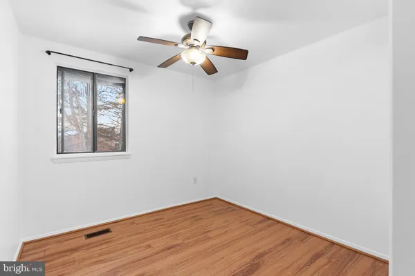 an empty room with wooden floor fan and windows