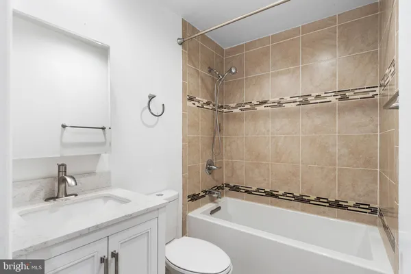 a bathroom with a granite countertop bathtub shower sink vanity and toilet