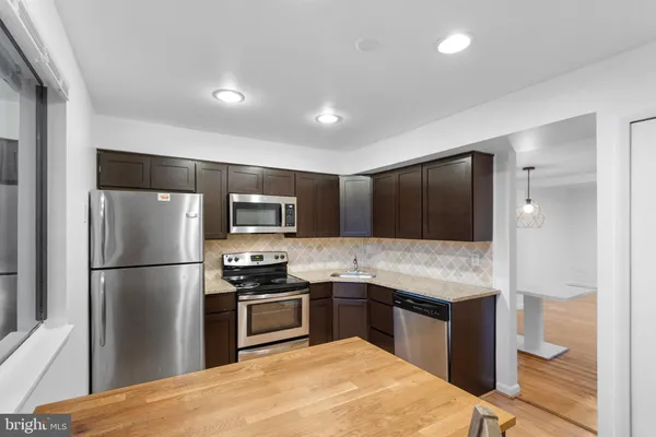 a kitchen with granite countertop a refrigerator and a stove top oven