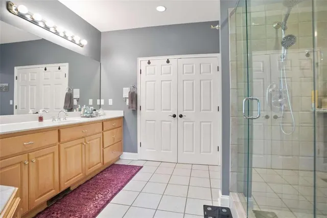 a spacious bathroom with a mirror a shower and double vanity