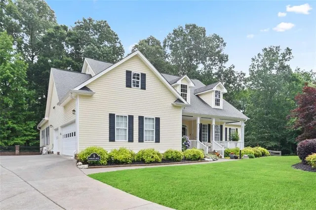 a view of a yard in front of a house with plants and large tree