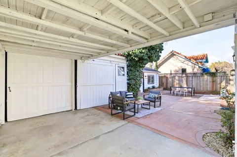 a view of a patio with table and chairs potted plants and wooden fence