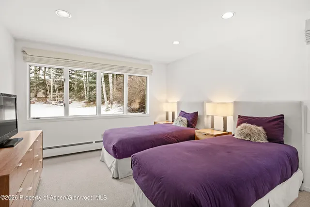 a bedroom with two beds and a large window