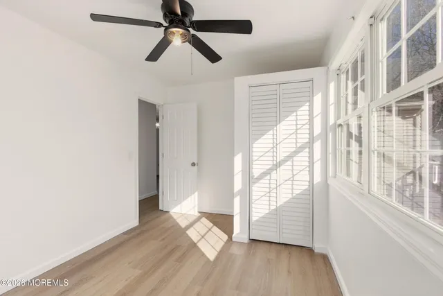 a view of empty room with wooden floor and fan