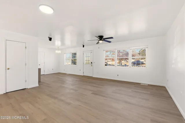 an empty room with kitchen view and windows