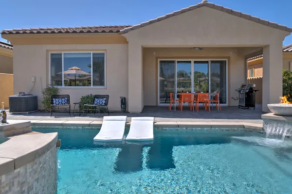 a view of a house with backyard sitting area and swimming pool