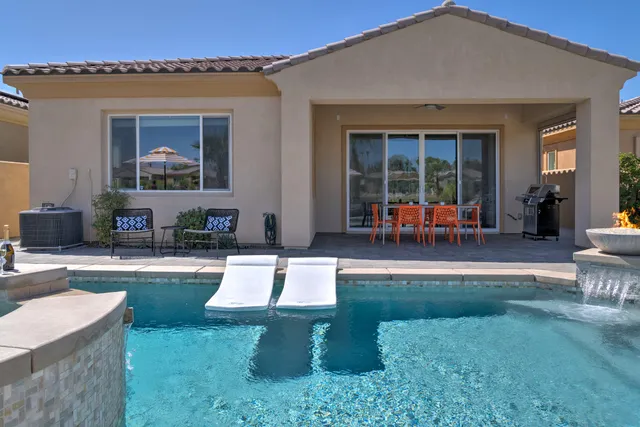 a view of a house with backyard sitting area and swimming pool