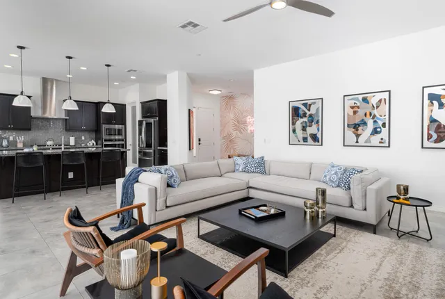 a kitchen with stainless steel appliances granite countertop a stove a sink dishwasher a refrigerator white cabinets and couches with wooden floor