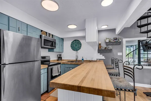 a kitchen with stainless steel appliances granite countertop a refrigerator a stove a sink dishwasher a dining table and chairs with wooden floor