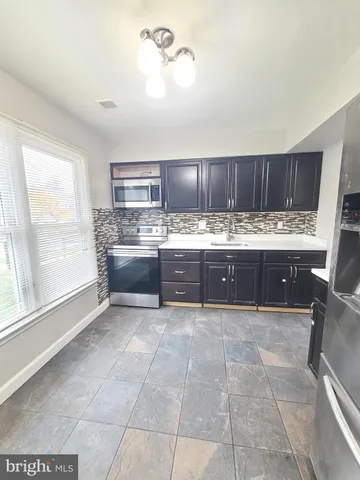 a large kitchen with kitchen island granite countertop a stove a sink and a microwave