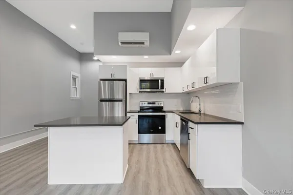 a kitchen with stainless steel appliances granite countertop a stove top oven a sink and white cabinets