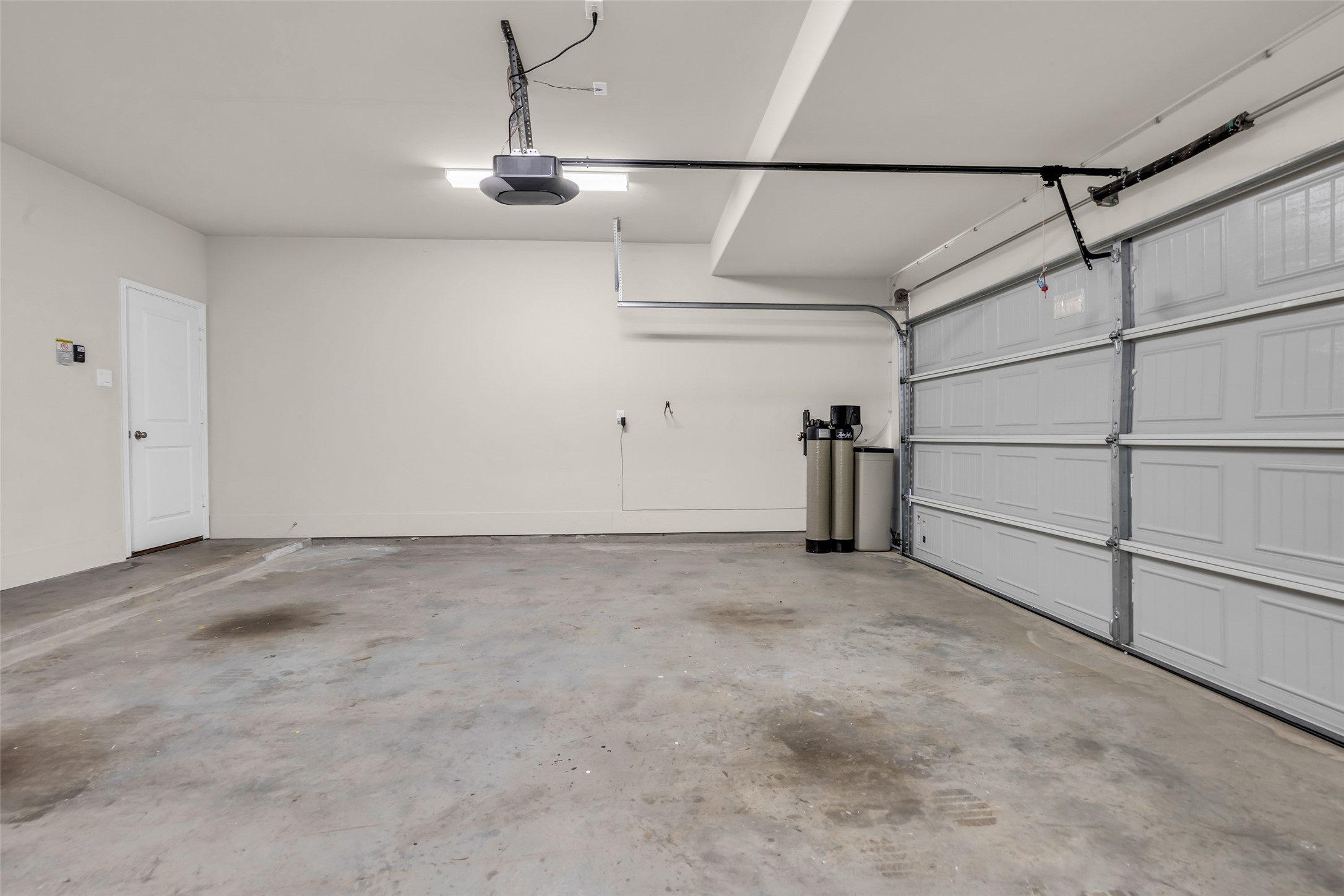 2344 Hagerman Road Conroe, TX 77384 - Photo 24 of 27 Spacious two-car garage with an electric garage door, offering ample room for parking and featuring a whole-house water softener system.
