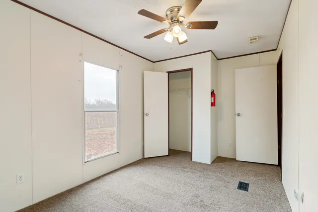 an empty room with windows and fan