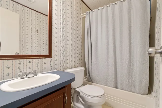a bathroom with a granite countertop sink toilet and a mirror
