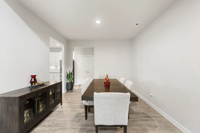 a kitchen with stainless steel appliances granite countertop a refrigerator a stove a sink a dining table and chairs