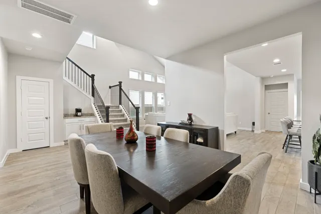 a large kitchen with stainless steel appliances granite countertop a stove top oven a sink a refrigerator and white cabinets