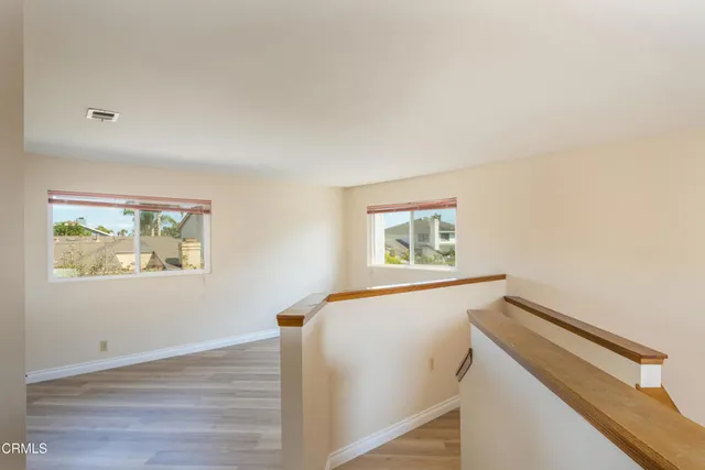 a view of hallway with window and wooden floor