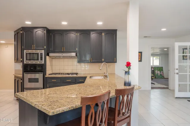 a kitchen with granite countertop kitchen island stainless steel appliances a stove refrigerator and cabinets