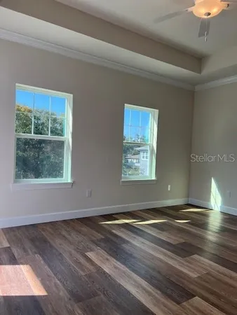 an empty room with wooden floor and windows