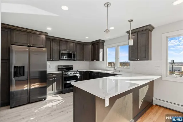 a kitchen with stainless steel appliances granite countertop a sink a stove and a refrigerator