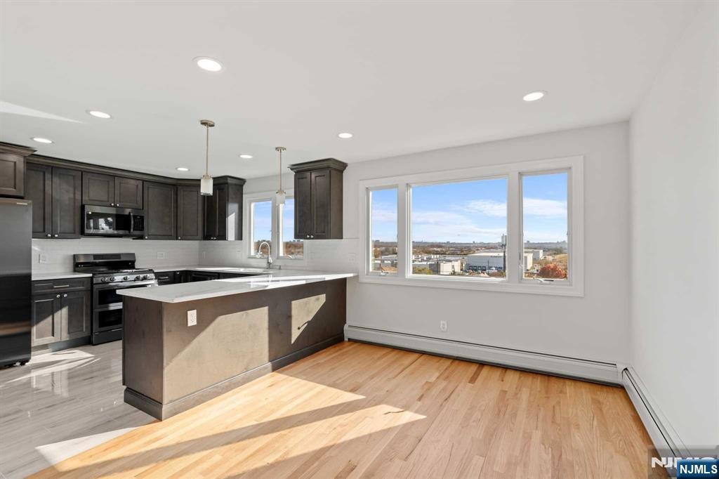 743 7th Street, Unit 1 Carlstadt, NJ 07072 - Photo 8 of 23 a large kitchen with stainless steel appliances granite countertop a stove a sink and a microwave