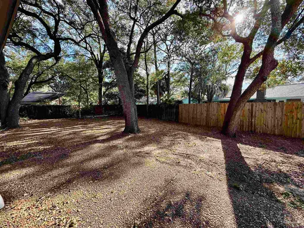 a view of a yard with wooden fence and a large tree