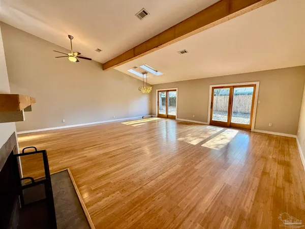a view of an empty room with window and wooden floor