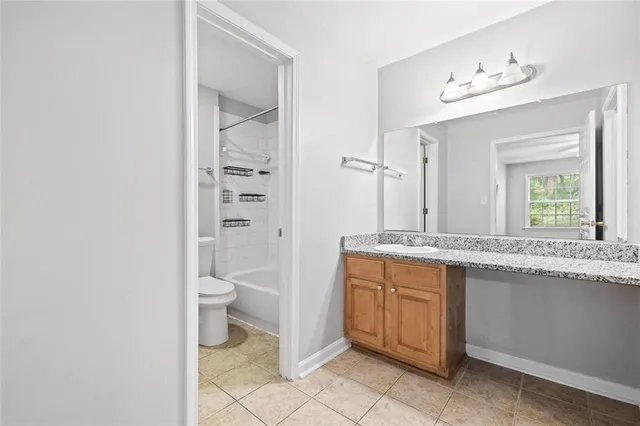 a bathroom with a granite countertop toilet a sink and a mirror