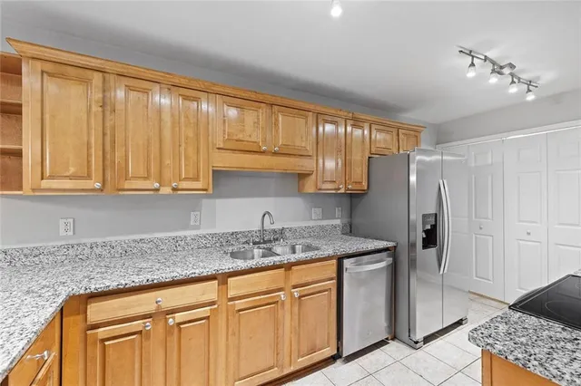 a kitchen with stainless steel appliances granite countertop a sink a refrigerator and cabinets with wooden floor