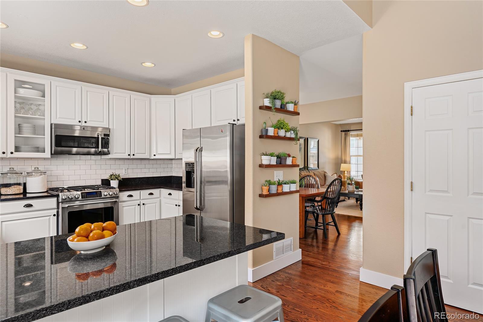 9441 South Hackberry Lane Highlands Ranch, CO 80129 - Photo 13 of 50 a kitchen with stainless steel appliances granite countertop a refrigerator a stove top oven a sink a dining table and chairs with wooden floor