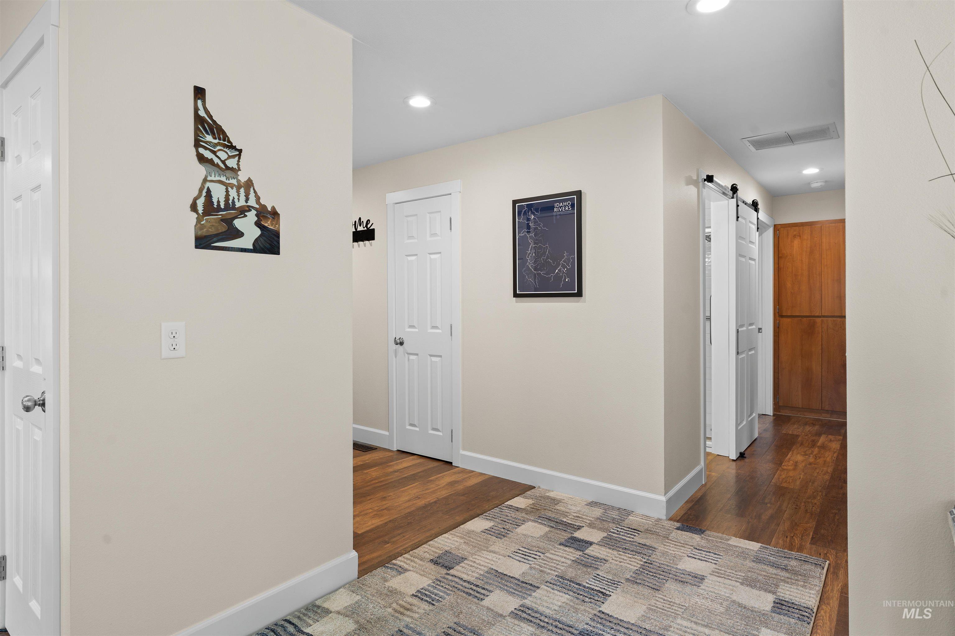 20015 Clark Street Juliaetta, ID 83535 - Photo 11 of 46 Hallway featuring wood-finish flooring, white trim, recessed lighting, and a barn door