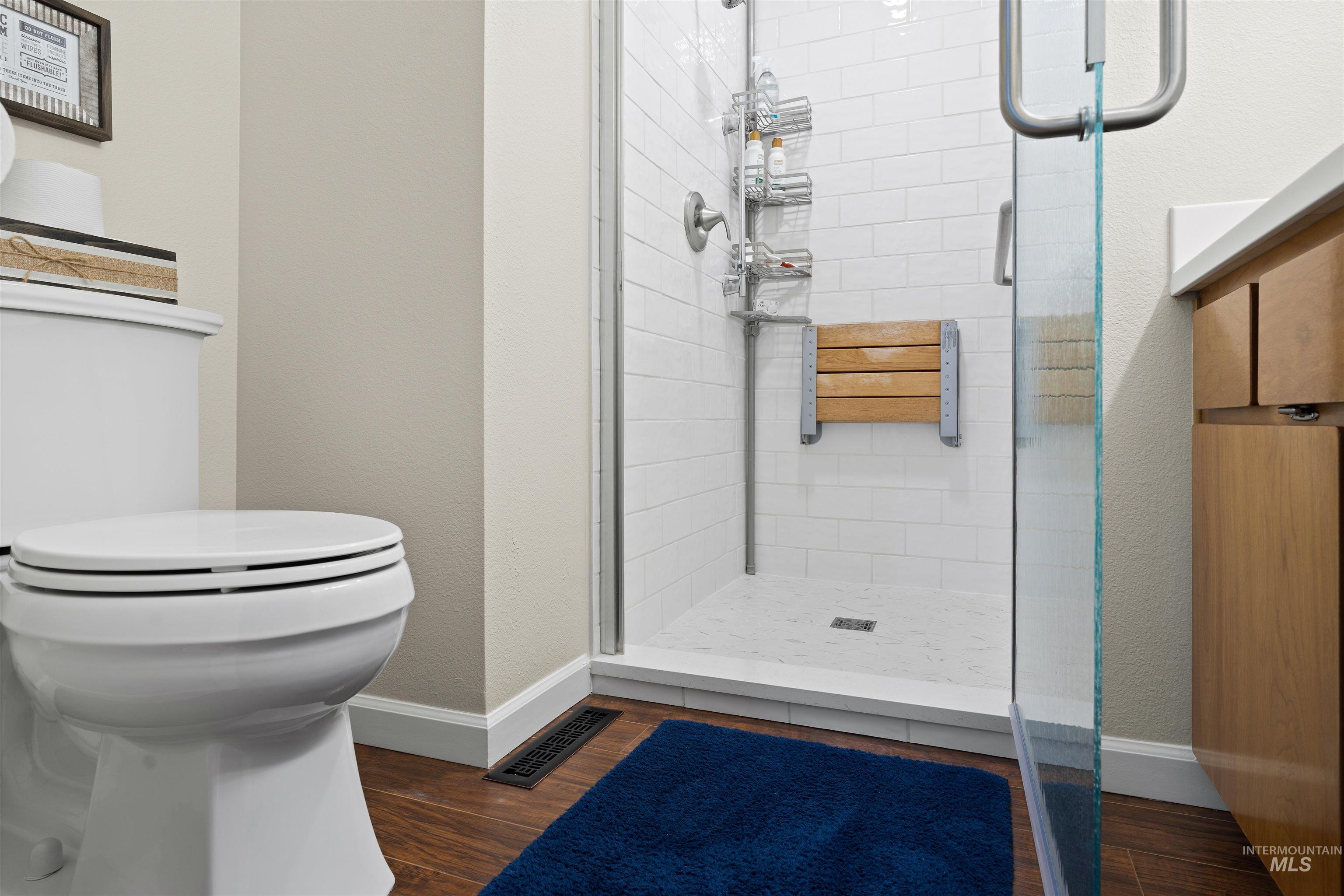 20015 Clark Street Juliaetta, ID 83535 - Photo 16 of 46 Walk-in shower featuring subway tile surround, built-in wooden bench, and glass enclosure