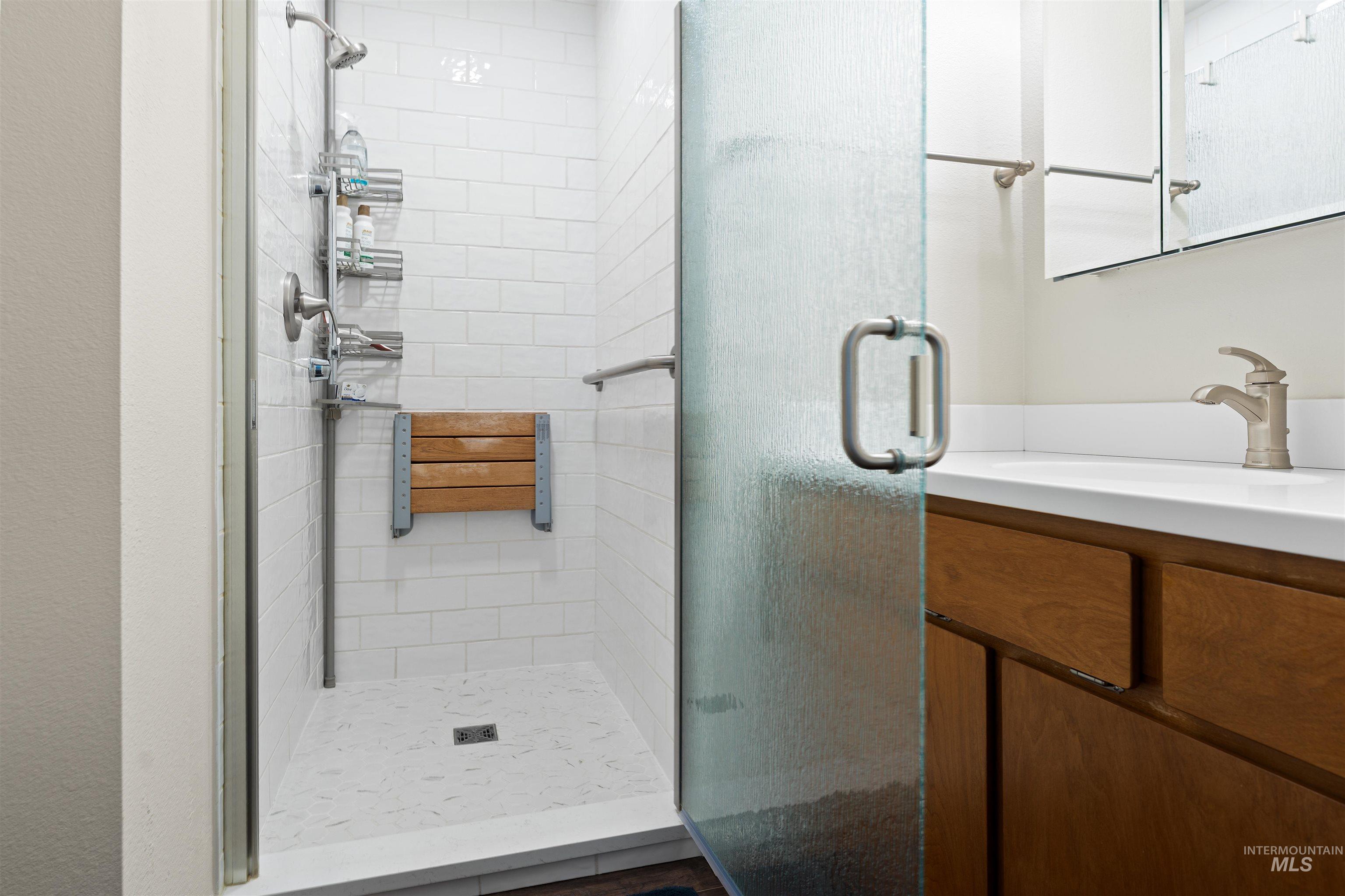 20015 Clark Street Juliaetta, ID 83535 - Photo 17 of 46 Shower enclosure featuring subway tile walls, a built-in folding wood seat, and a handheld shower fixture
