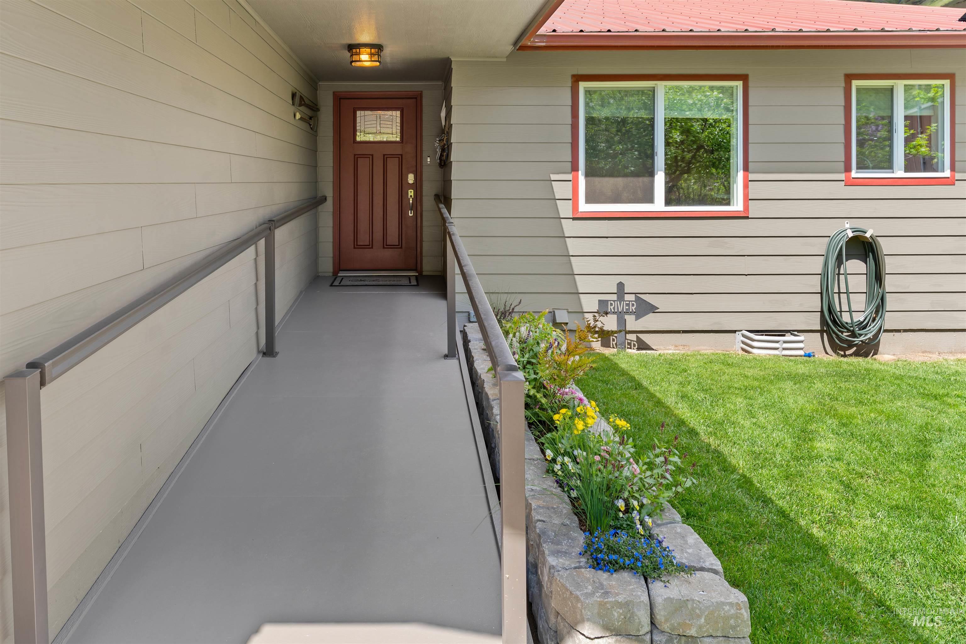 20015 Clark Street Juliaetta, ID 83535 - Photo 25 of 46 Front entry featuring a sloped access ramp with metal handrails, a paneled wood-finish door with glass inserts, and an overhead sconce light