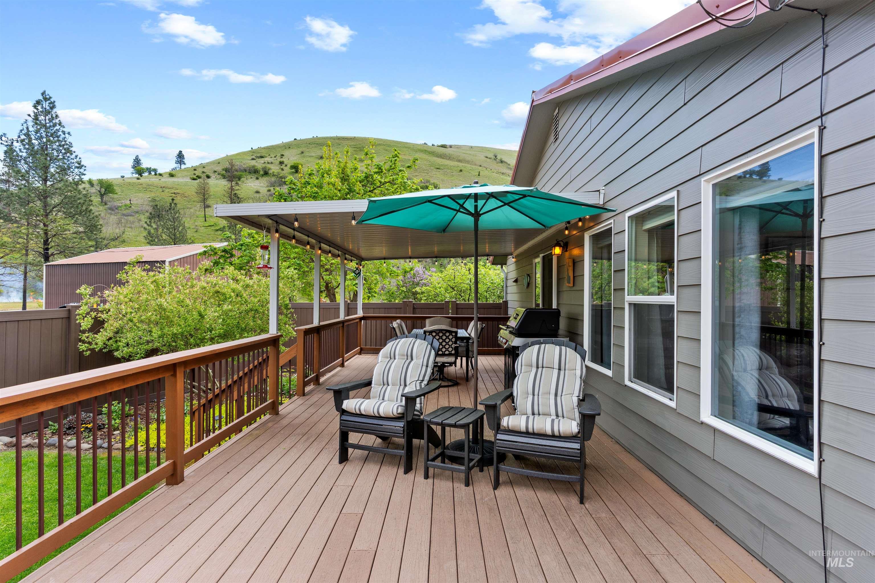 20015 Clark Street Juliaetta, ID 83535 - Photo 26 of 46 Expansive wood-finish deck with a brown railing system, partially covered by a metal patio awning