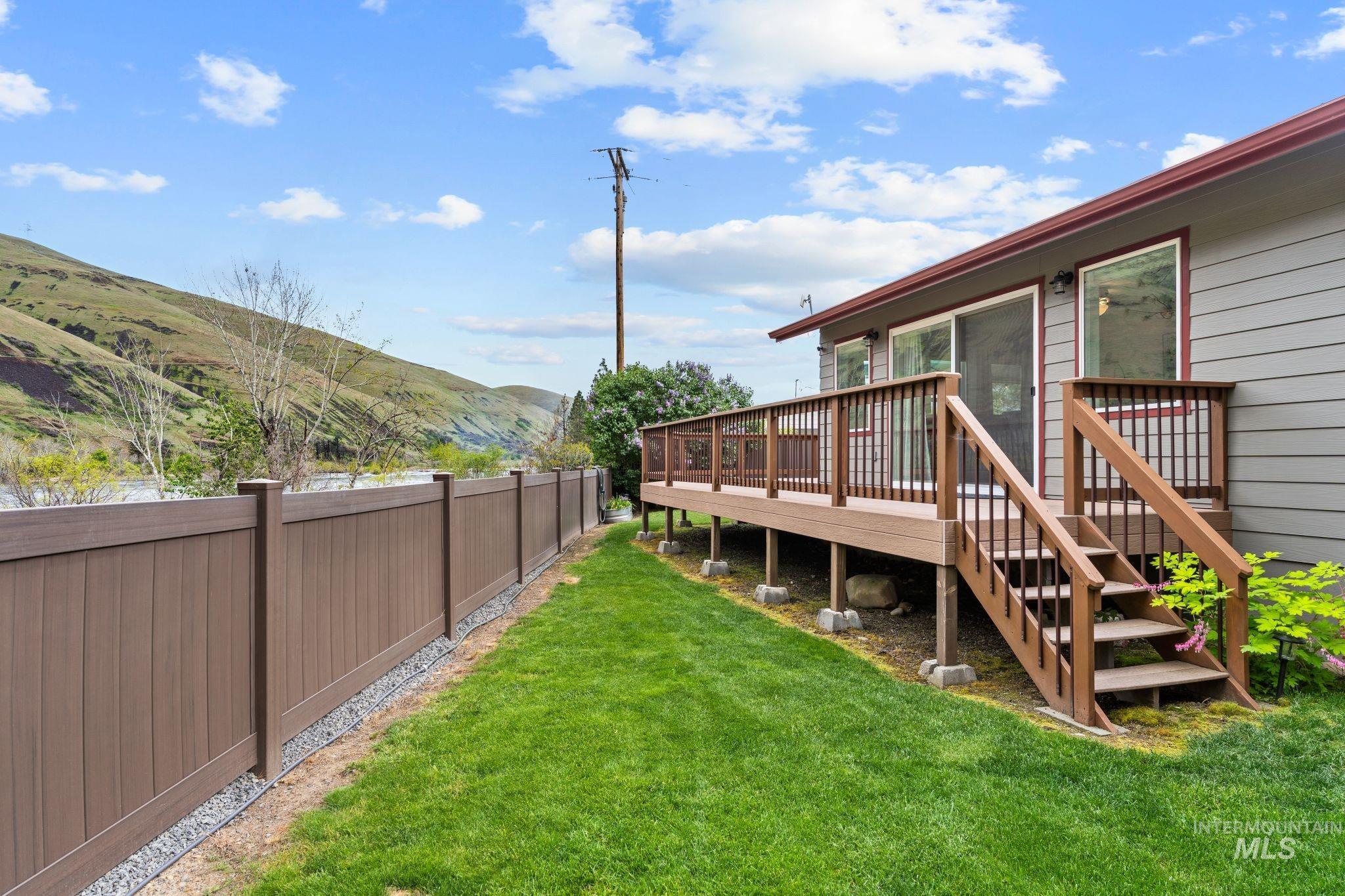 20015 Clark Street Juliaetta, ID 83535 - Photo 40 of 46 Rear exterior featuring a multi-level deck with wood-tone railings and stairs, providing direct access to the manicured lawn