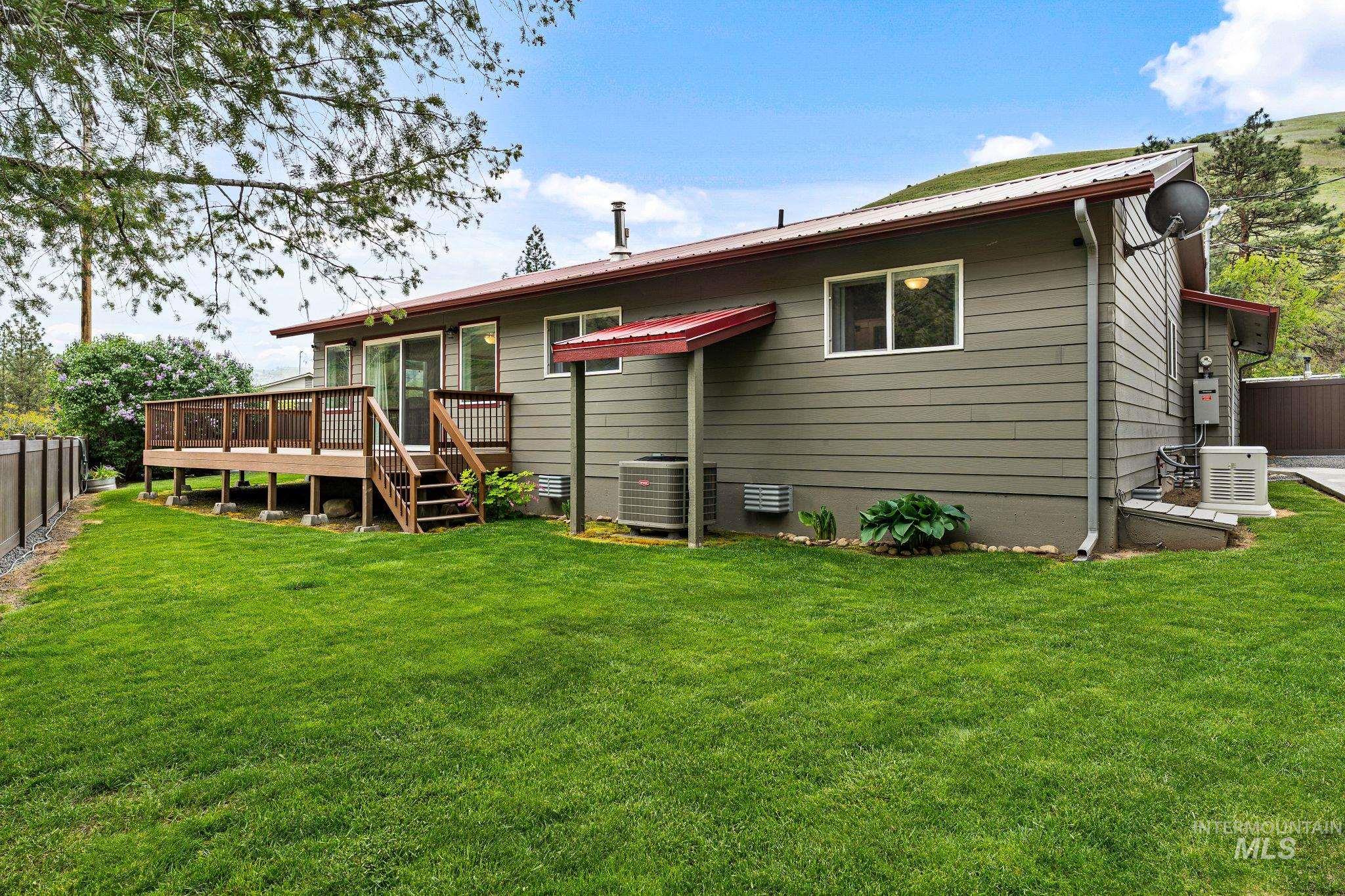 20015 Clark Street Juliaetta, ID 83535 - Photo 41 of 46 Spacious rear yard featuring a wood deck with stairs, a sliding glass door, multiple windows, and a red metal roof