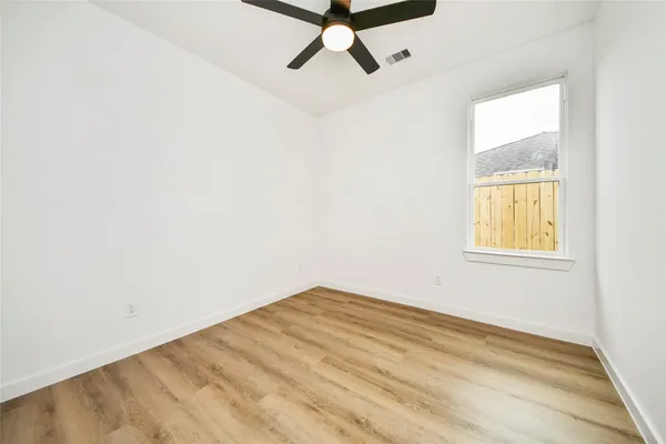 an empty room with a window and a ceiling fan