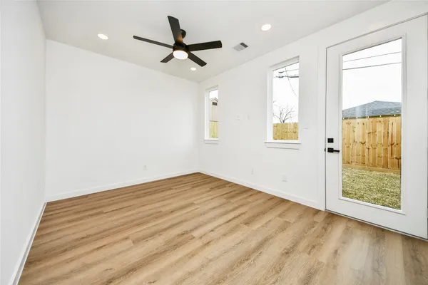 a view of empty room with wooden floor and fan