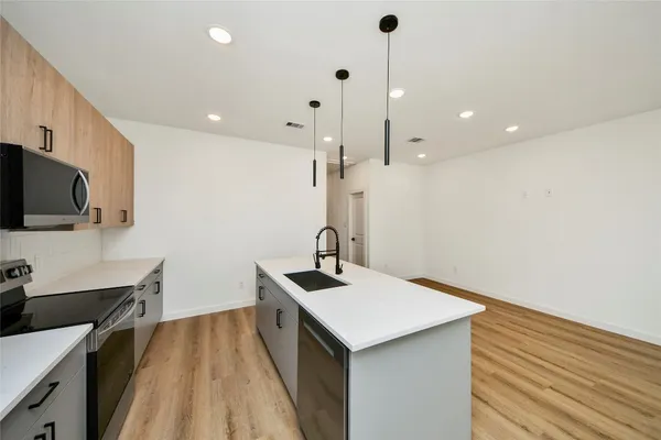 a kitchen with a sink stainless steel appliances and wooden floor