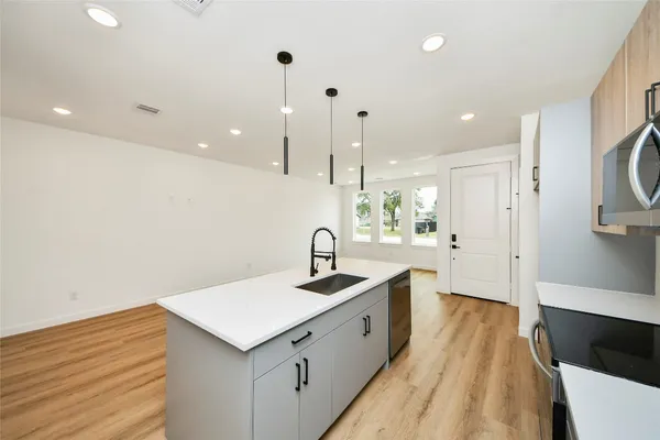 a large kitchen with a sink and dishwasher a stove top oven with wooden floor