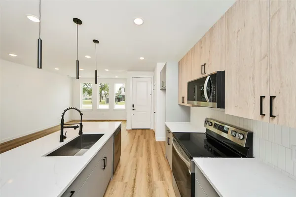 a kitchen with stainless steel appliances granite countertop a sink a stove and a refrigerator