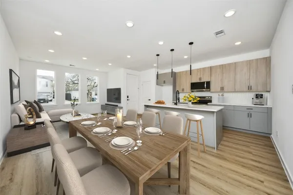 a open dining room with stainless steel appliances kitchen island granite countertop a stove a sink a refrigerator and white cabinets with wooden floor