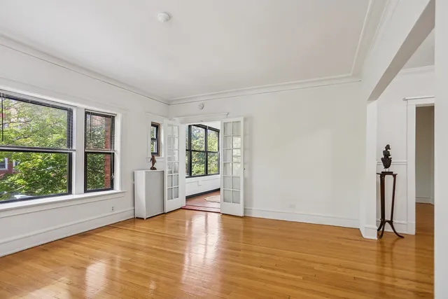 a view of an empty room with a window and wooden floor