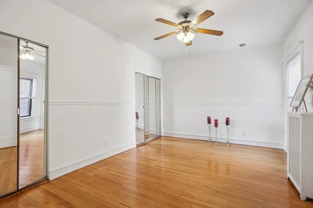 an empty room with wooden floor and ceiling fan