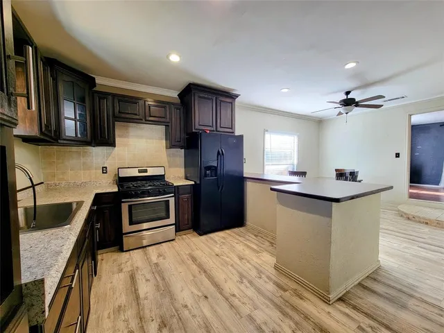 a kitchen with stainless steel appliances kitchen island granite countertop a stove a sink and a refrigerator