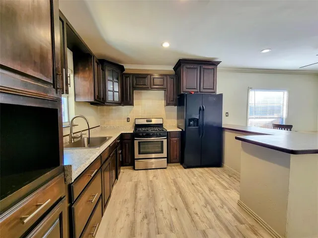 a kitchen with granite countertop a refrigerator stove and sink