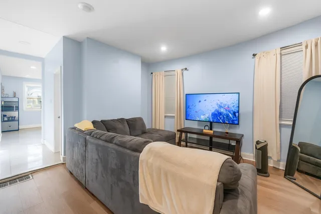 a living room with furniture a flat screen tv and a refrigerator