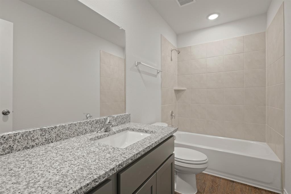 3117 Harmony Way Cleburne, TX 76031 - Photo 14 of 23 a bathroom with a granite countertop sink a toilet and shower